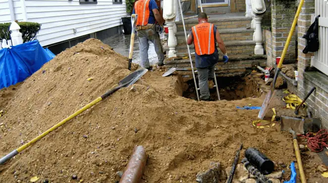 Contractors performing foundation protection and exterior drainage excavation near residential home steps in Staten Island, NY